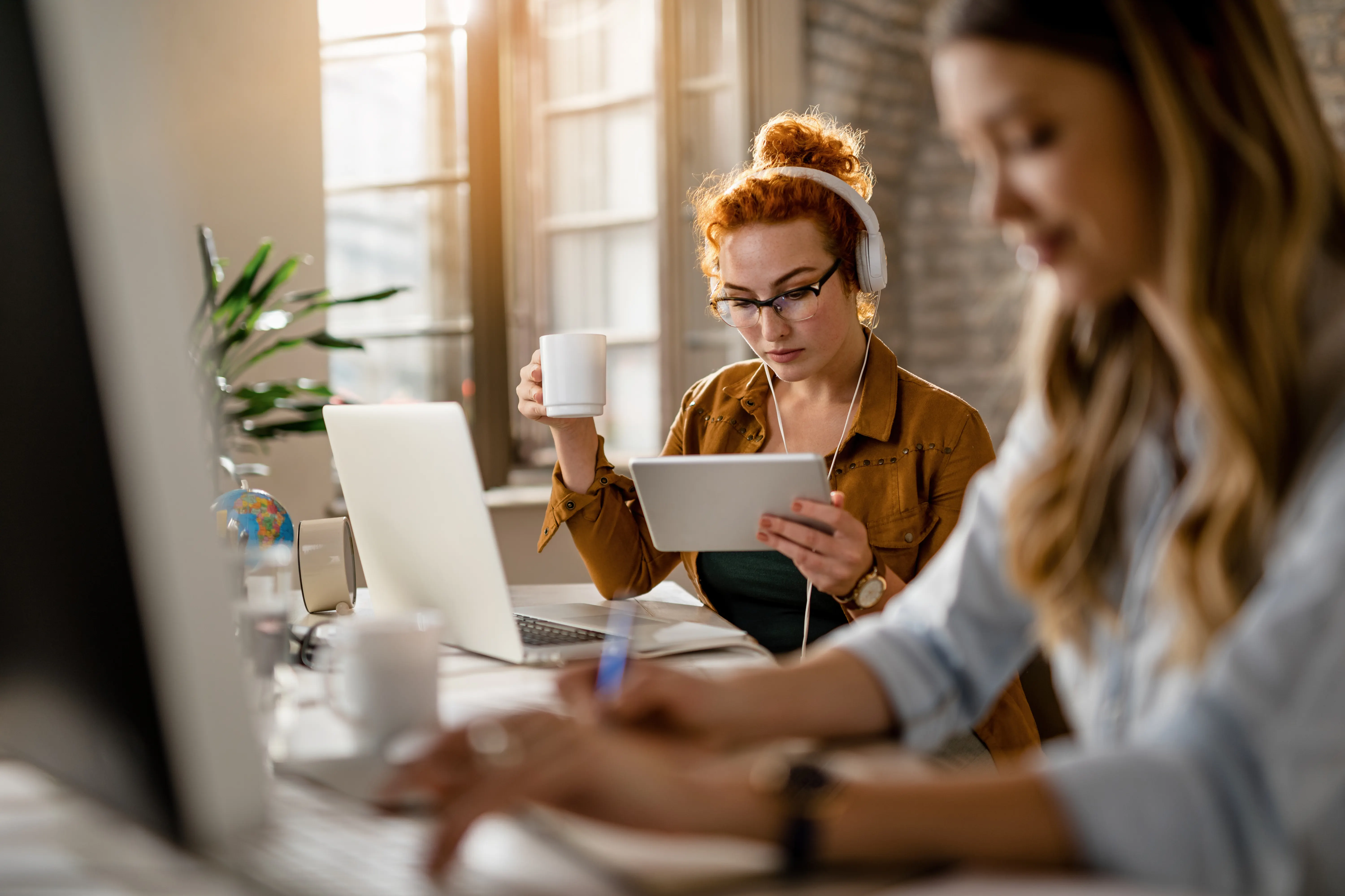 Zwei Kolleginnen arbeiten am Laptop und Tablet
